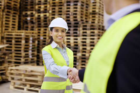 Supervisor and trainee shaking hands in distribution warehouse