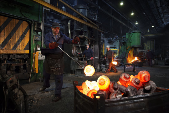 Forge worker swings finished forged component onto pallet 