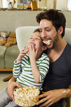 Father and young son with mouthfuls of popcorn