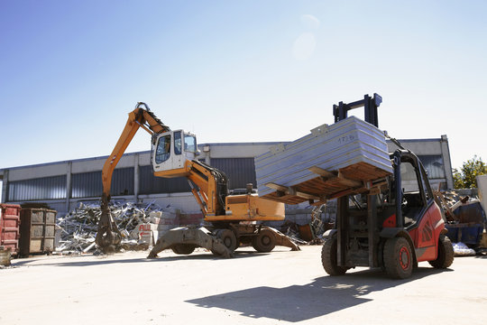 Crane grab and fork lift truck sorting and moving metals in scrap yard