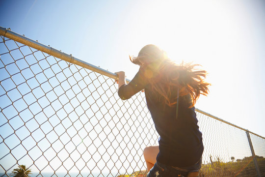 Young woman messing about on wire fence