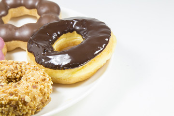 Donut glazed chocolate strawberry peanut on white dish on backgr