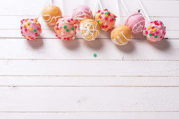 Cake pops on white  painted wooden background.