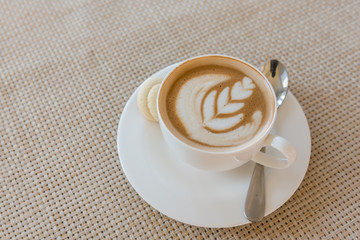 white cup of latte coffee on wooden tray