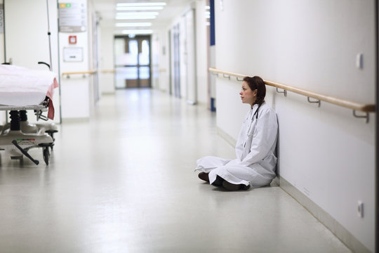 Female doctor sitting cross legged in hospital corridor