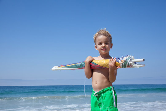 Male toddler holding sun umbrella