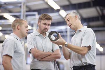 Manager discussing component in engineering factory