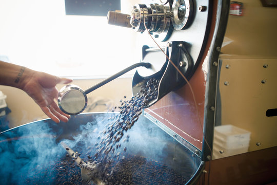 Female hand using industrial coffee roasting machine in cafe