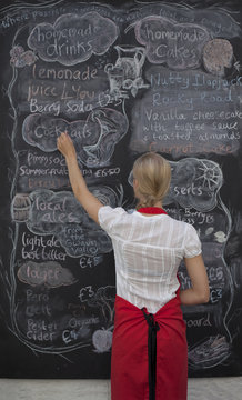 Waitress writing on blackboard menu in cafe