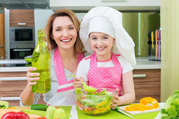 Happy mother and daughter cooking a salad.