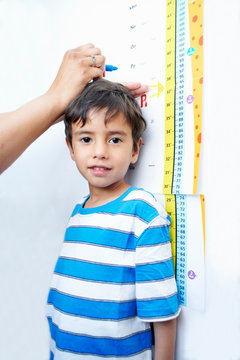 Boy standing against height chart being measured