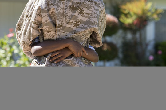 Cropped rear view of female soldier hugging son on homecoming