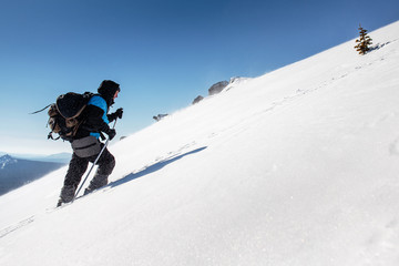 A male climber , in full gear and equipment, climbs up a snowy s
