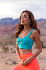 Attractive fashionable young woman in the desert walking in pink skirt