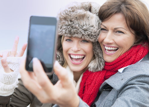Two female friends taking self portrait at coast, Thurlestone, Devon, UK