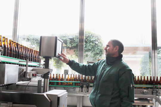 Brewery worker operating bottling machine