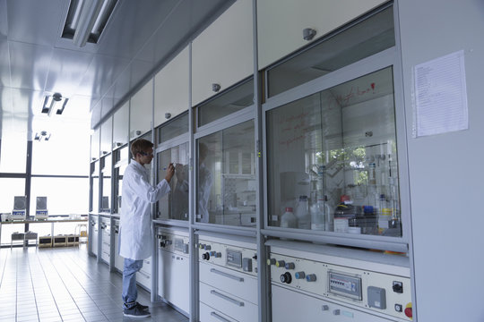 Young Male Scientist Writing On Fume Cupboard Window