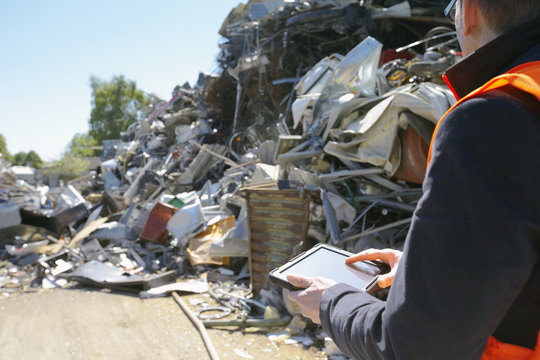 Foreman using digital tablet at scrap metal recycling plant