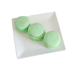 Green pistachio sweet macaroons, french traditional, cream,  white plate, close up, isolated on a white background