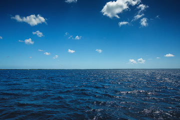 White fluffy clouds blue sky above a surface of the sea