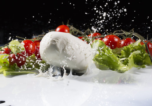 Vine tomatoes, mozzarella and lettuce leaf splashing into milk
