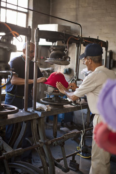 Hat makers stretching fabric in workshop