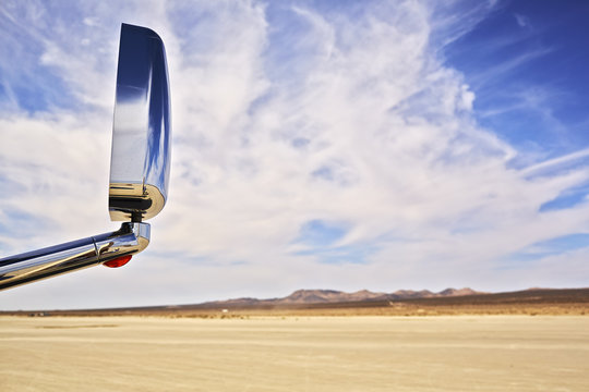 View of car wing mirror and arid landscape