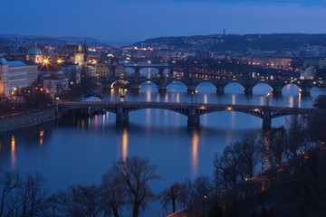 Evening Picture over Prague bridges and riverbank on the Vltava river with Charles bridge included in twilight during the blue hour. Historical downtown of Prague, capital of Czech Republic in Europe.