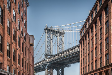 Manhattan bridge seen from narrow buildings on a sunny day
