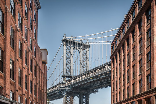 Fototapeta Manhattan bridge seen from narrow buildings on a sunny day