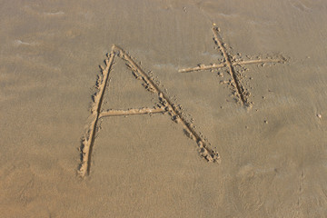 A+ sign written on sandy beach.