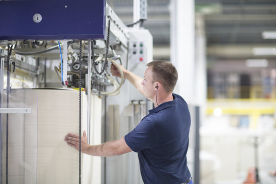 Worker using machine in paper packaging factory