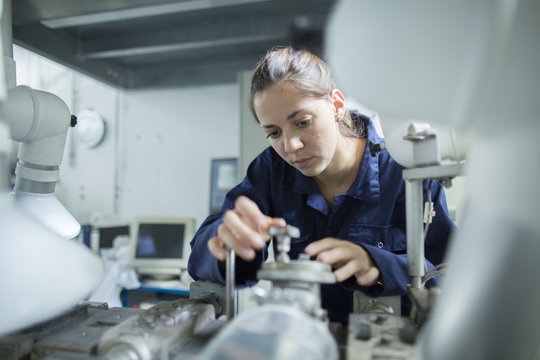 Female engineer turning valves on factory industrial piping