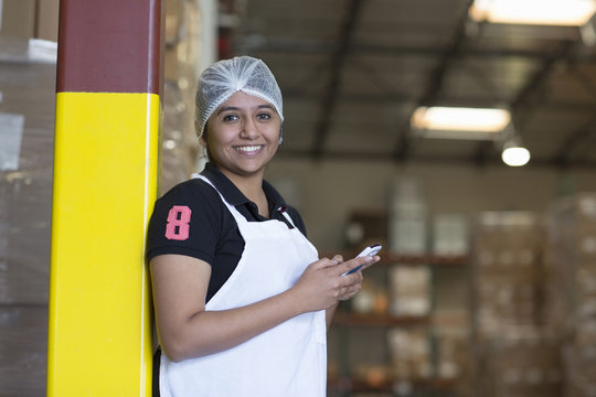 Portrait of female factory worker using cell phone