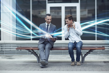 Businessman and young man watching digital tablet and waves of illumination