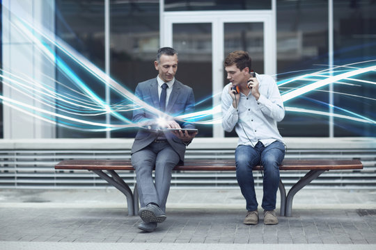 Businessman and young man watching digital tablet and waves of illumination