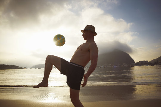 Mid adult man playing keepy uppy on Botafogo beach, Rio De Janeiro, Brazil