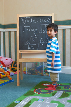 Boy standing beside blackboard with algebra