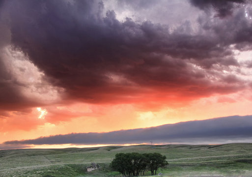 Roll cloud hangs low in the distance with sunset colors reflecting ongoing storm convection, Lexington, Nebraska, USA