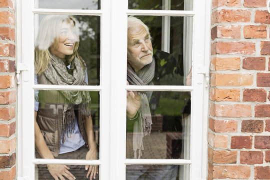 Father and daughter looking through window