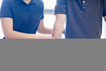 Man walking supported by rails, guided by therapist