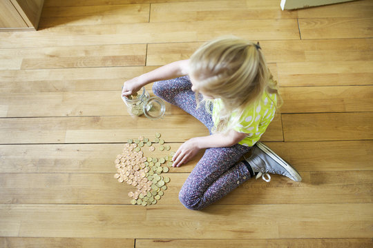 Girl counting coins from savings jar