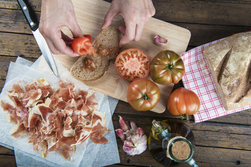 Cocinero untando tomate en una rebanada tostada de pan casero con ajo y aceite de oliva para...