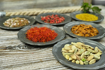 Cardamom, red saffron,- spices and herbs in metal bowls.