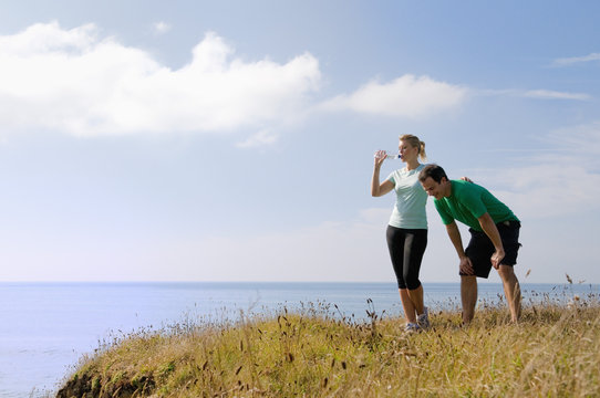 Mid adult couple resting from exercise, Thurlestone, Devon, UK