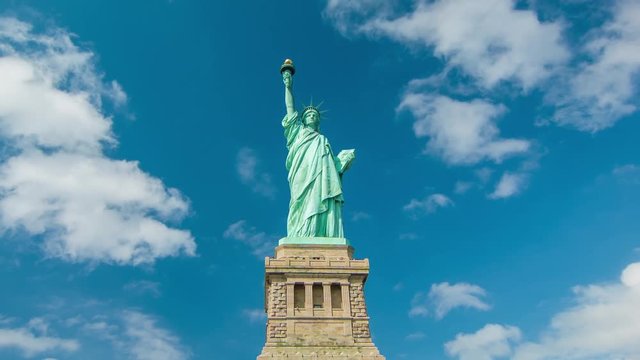 The Statue of Liberty (Wide Shot) with Moving White Clouds in a Blue Sky Background