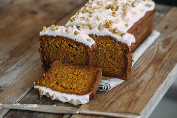 carrot cake with cream cheese and nuts on a wooden dark background