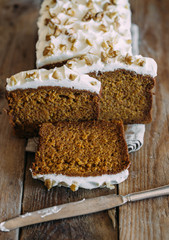 carrot cake with cream cheese and nuts on a wooden dark background