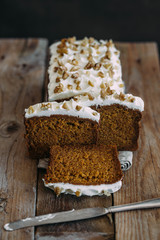 carrot cake with cream cheese and nuts on a wooden dark background