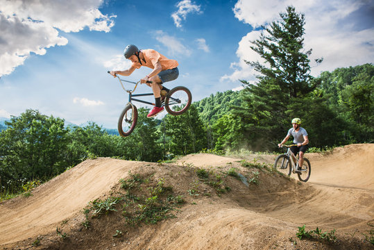 Two Male Friends Riding BMX And Mountain Bikes On Rural Pump Track